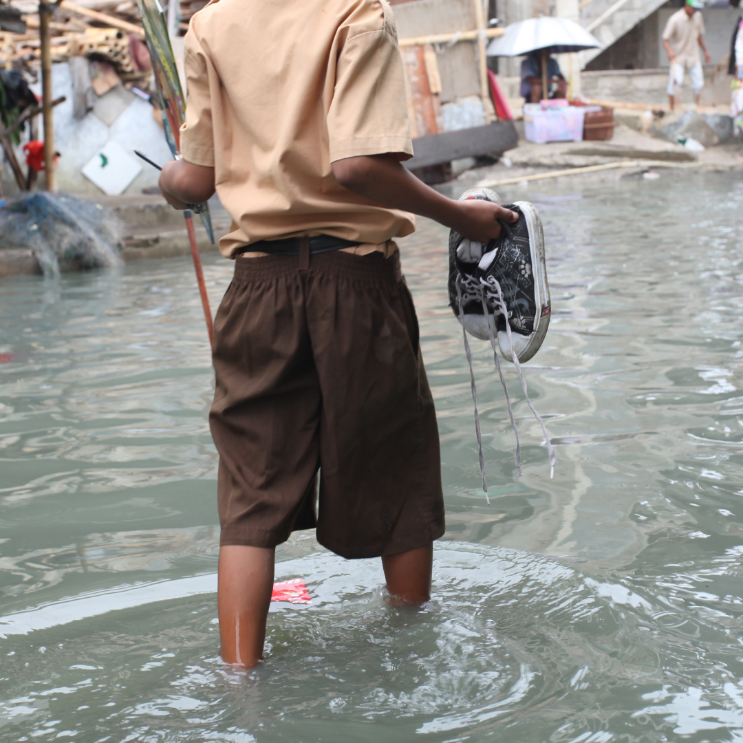 Pojke i Indonesien vadar genom högt vatten – slutsatser FN:s delrapport om klimatet
