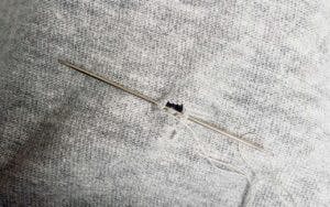 Laga litet hål i tröjan med nål och tråd.