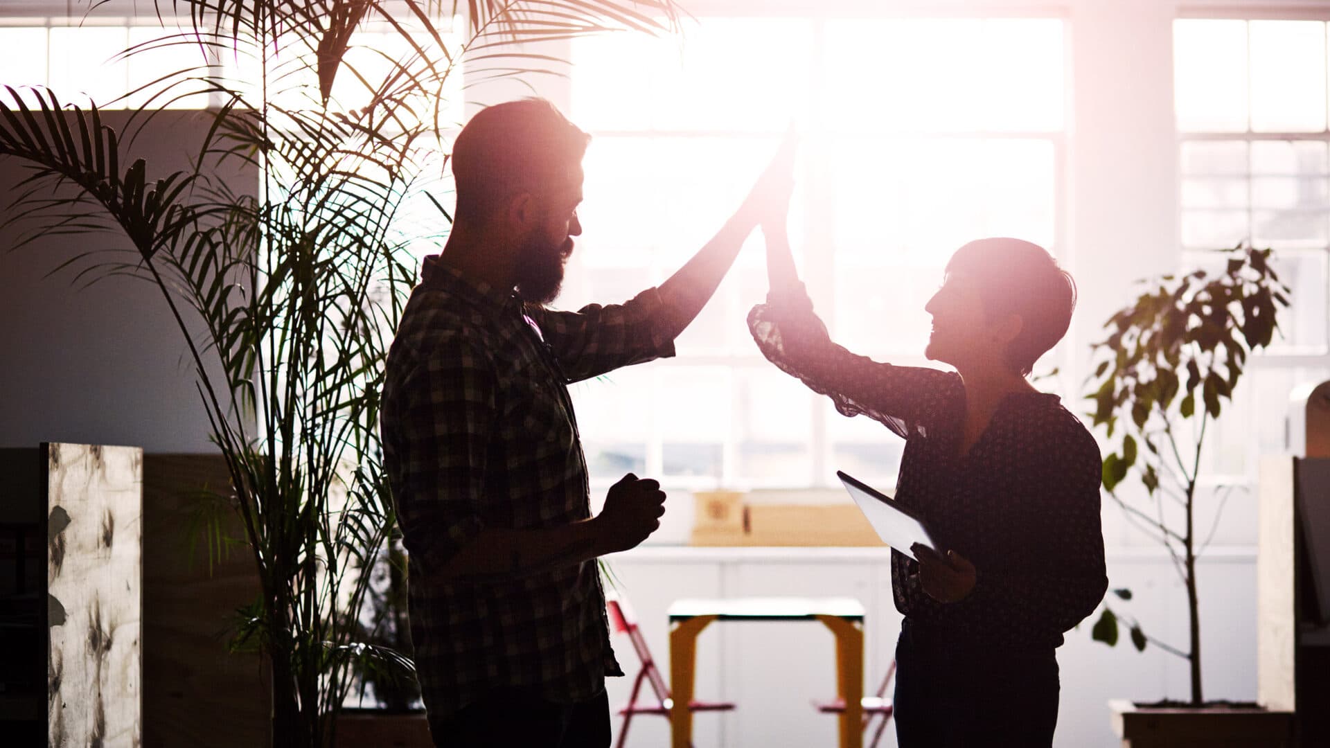 Två kolleger gör high-five på ett kontor.