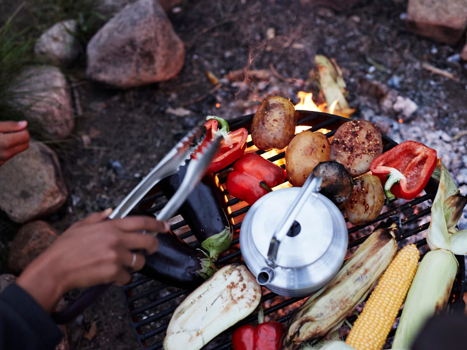 Cropped hand of woman cooking food on barbecue grill at campsite