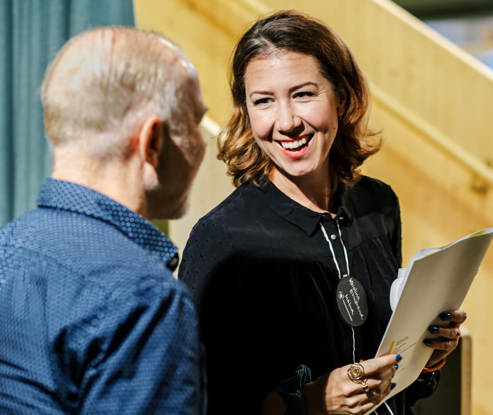 Bilden visar två personer som verkar vara i en konversation. Kvinnan till höger i bilden ler och ...