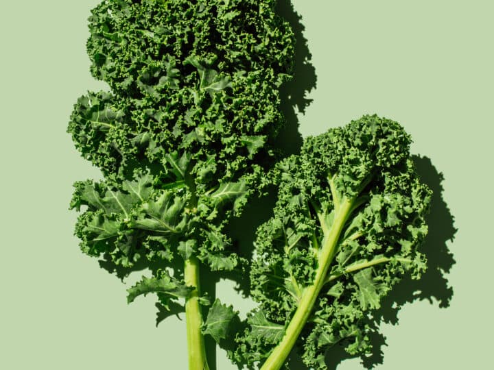 Fresh green organic kale leaves on green background. Healthy food, diet and detox concept. Flat lay, ...