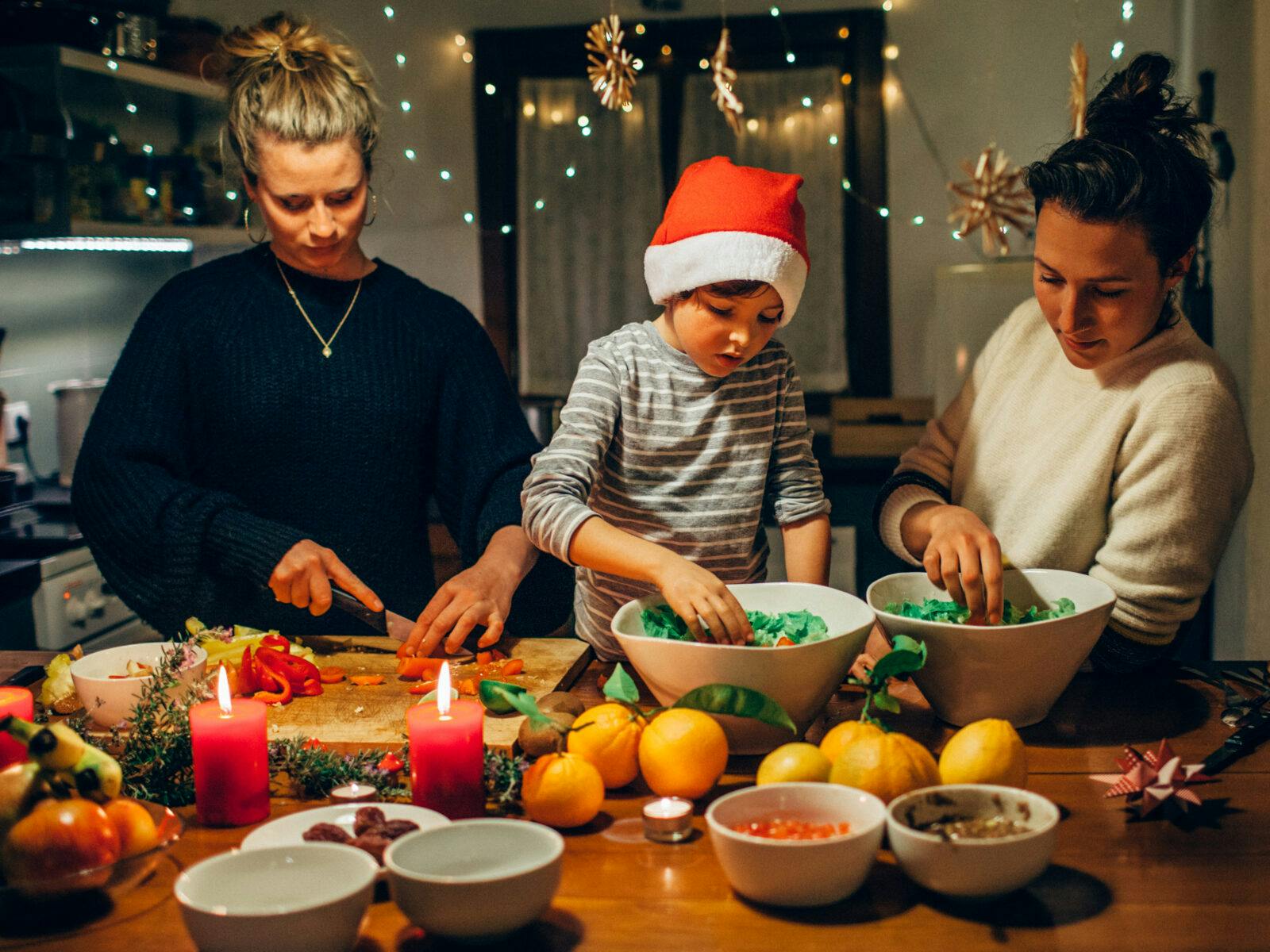 Tips för en hållbar jul. En familj med ett barn i tomtemössa lagar julmat.