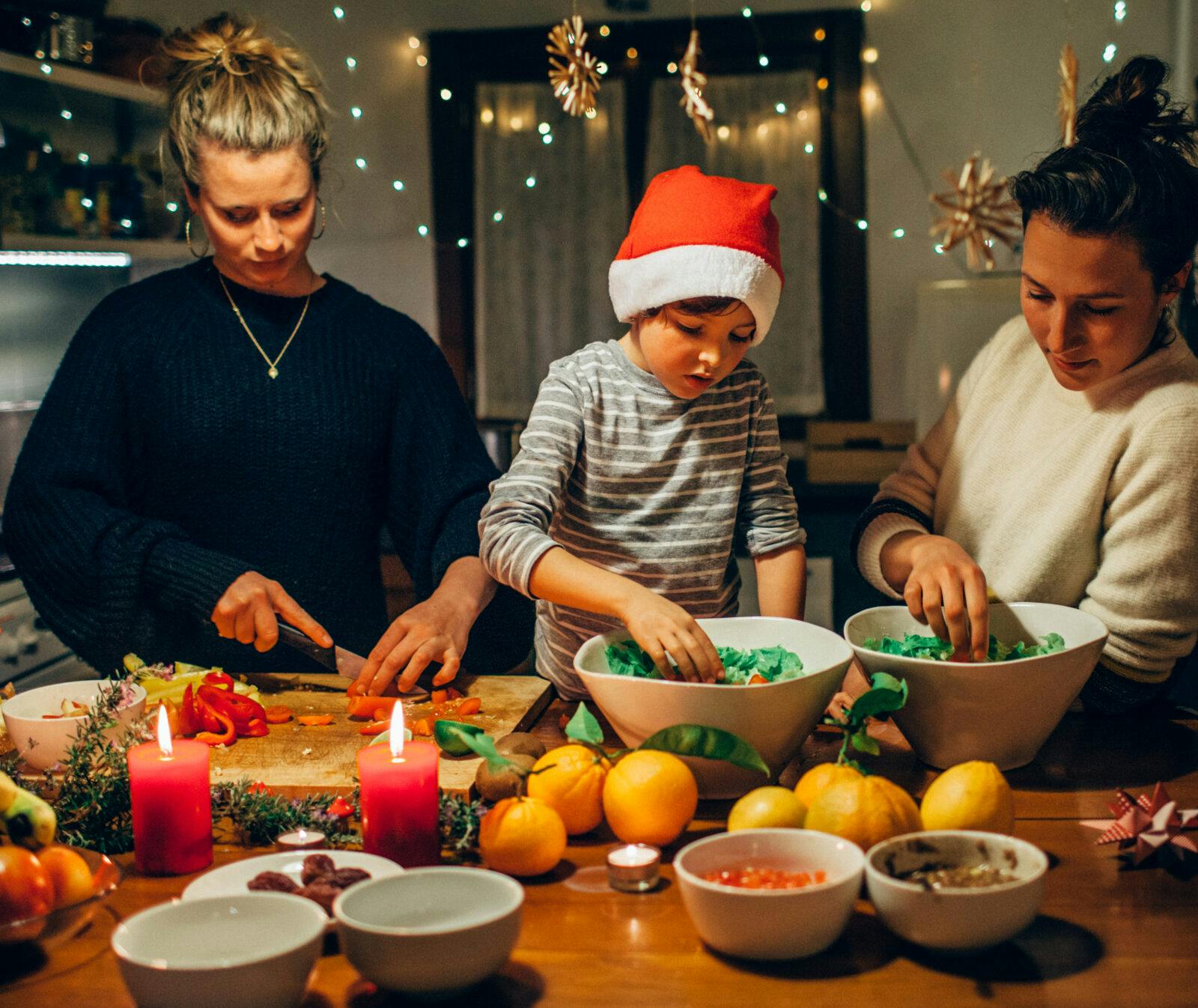 Tips för en hållbar jul. En familj med ett barn i tomtemössa lagar julmat.