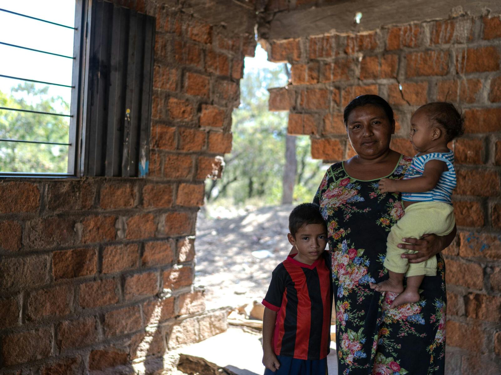 Luz Angela Uriana står i sitt hus med sin son Moises Guette och sin dotter Saray Guette. De dagliga gruvsprängningarna har gjort att en del av husväggen har rasat.