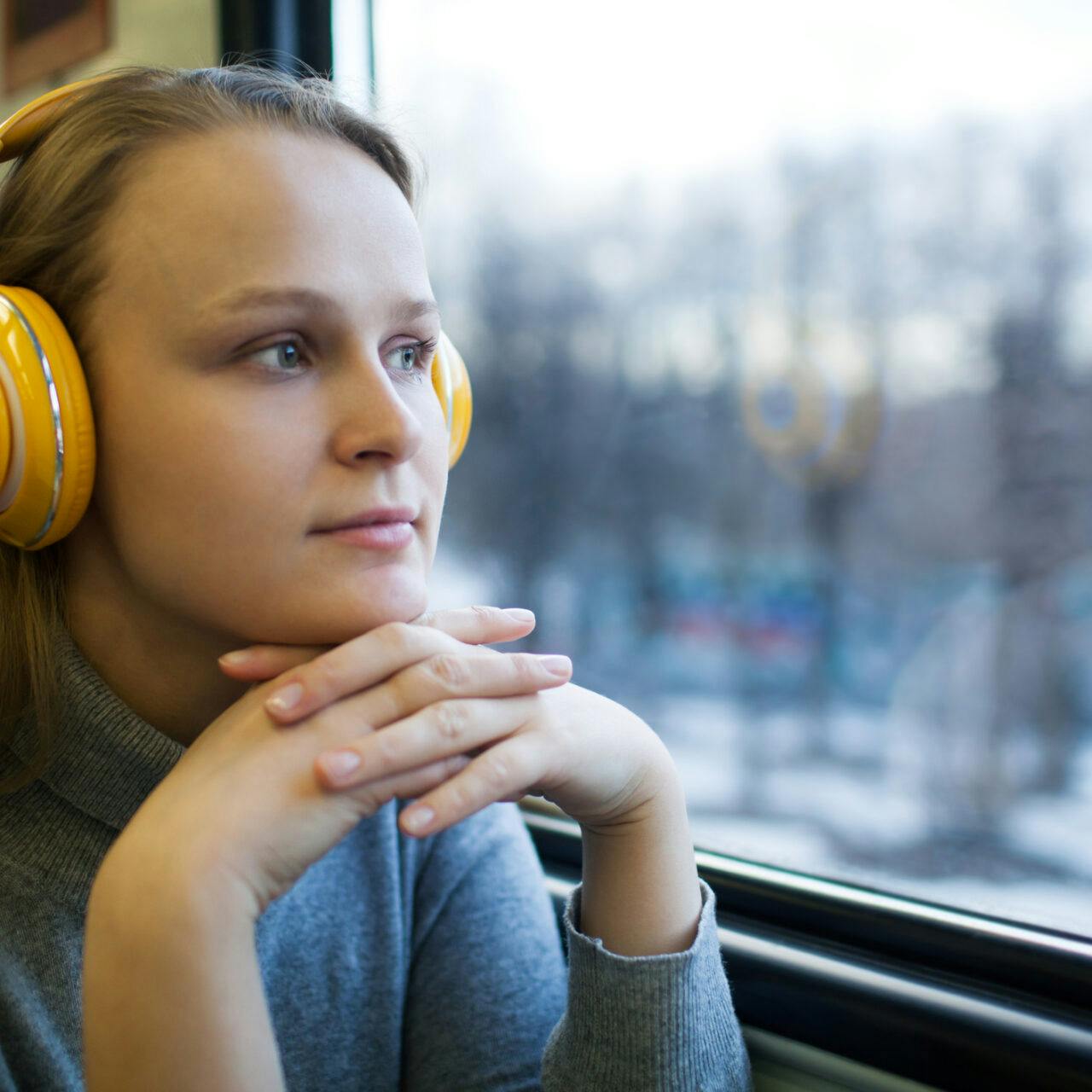 Ung kvinna ser ut genom tågfönster.