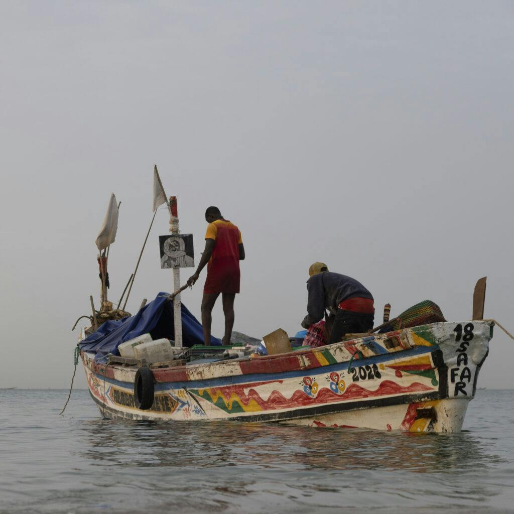Fiskebåt med fiskare nära stranden i Mbour, Senegal. småskaligt fiske