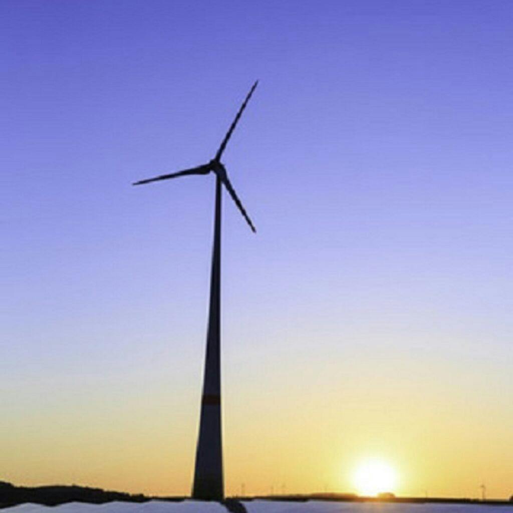Vindkraftsverk syns i soluppgången.