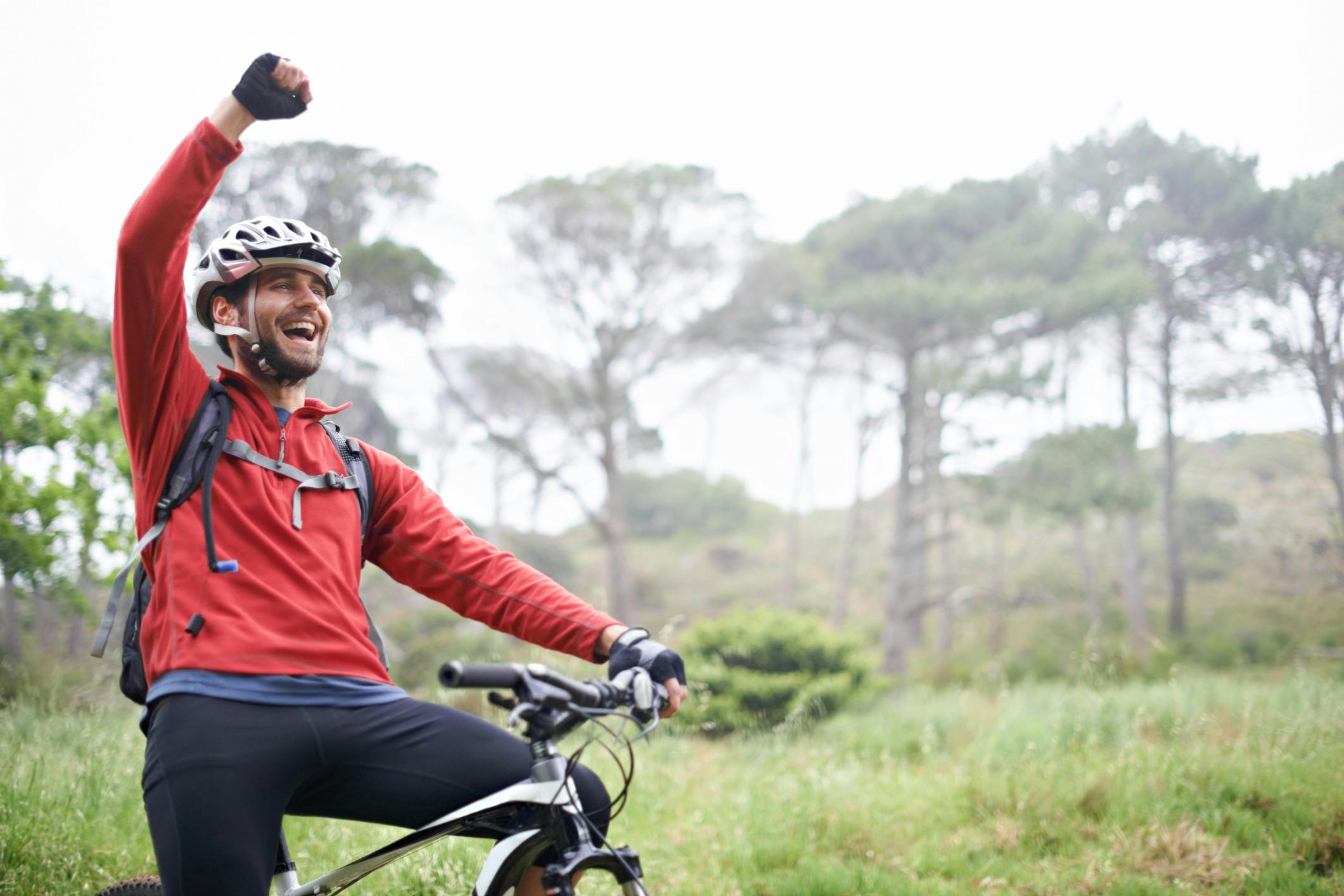 A young male athlete pumping his fist in the air after conquering a mountain biking trail