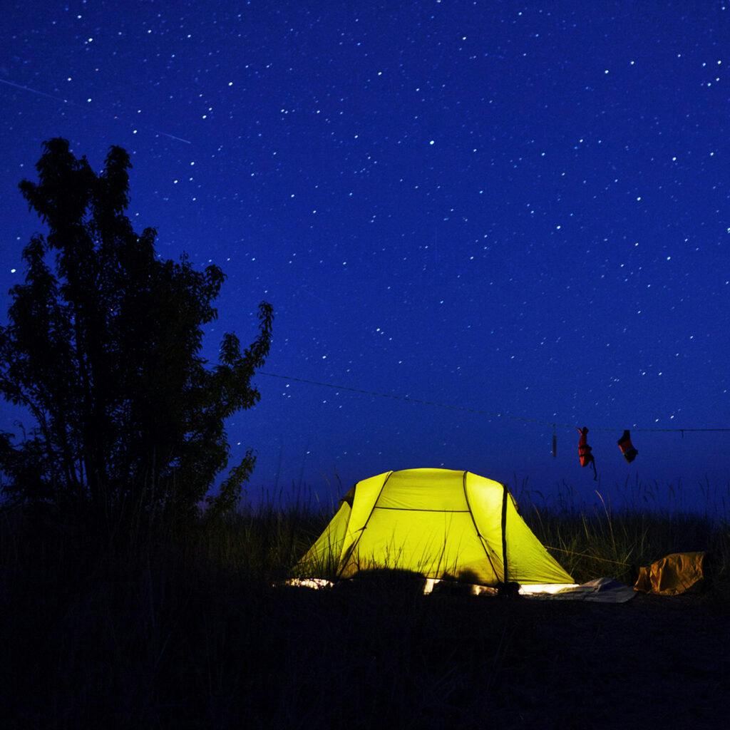 Ett upplyst tält framför en stjärnhimmel.