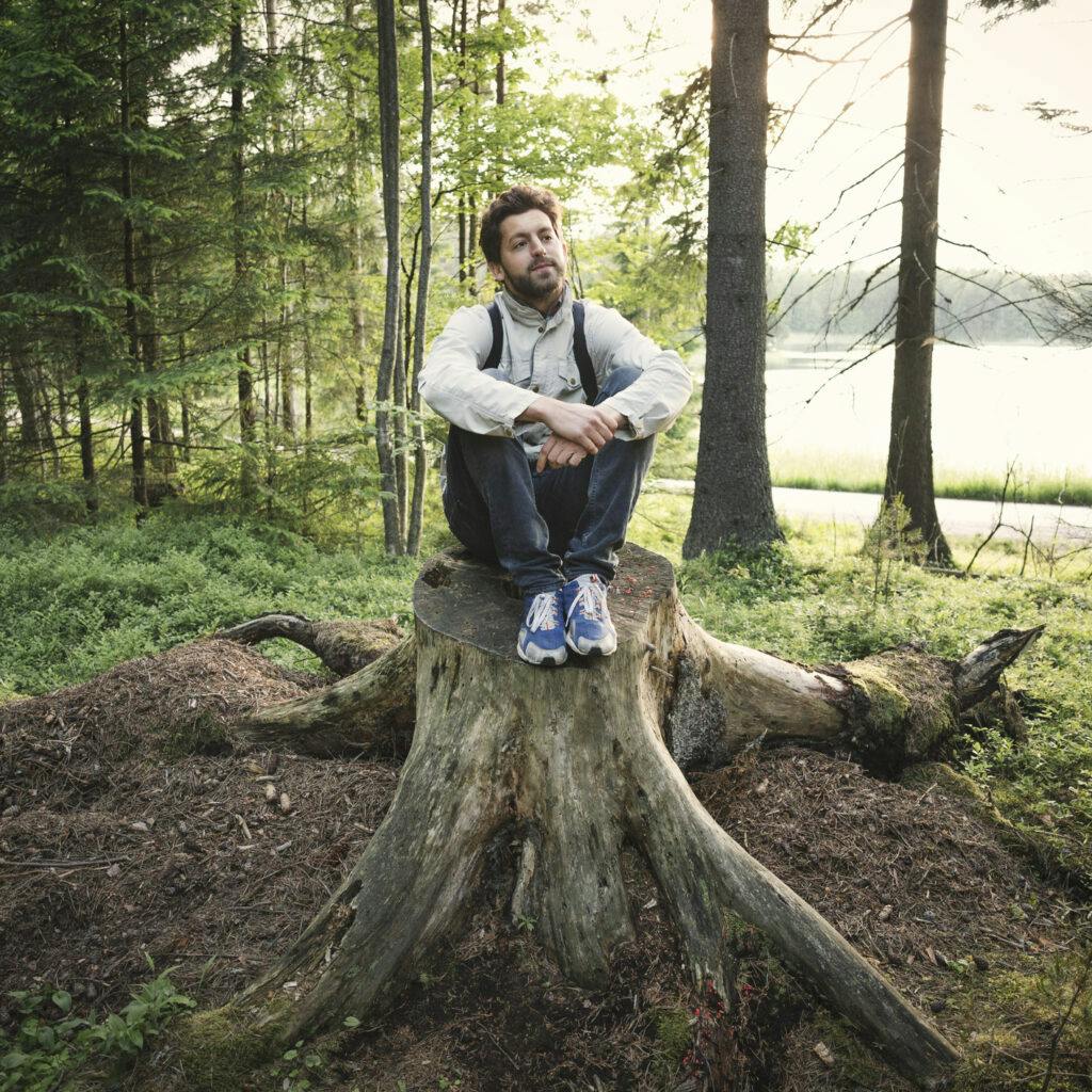 Man som sitter på stubbe i skogen. Bilden har använts till Uppdrag skog.