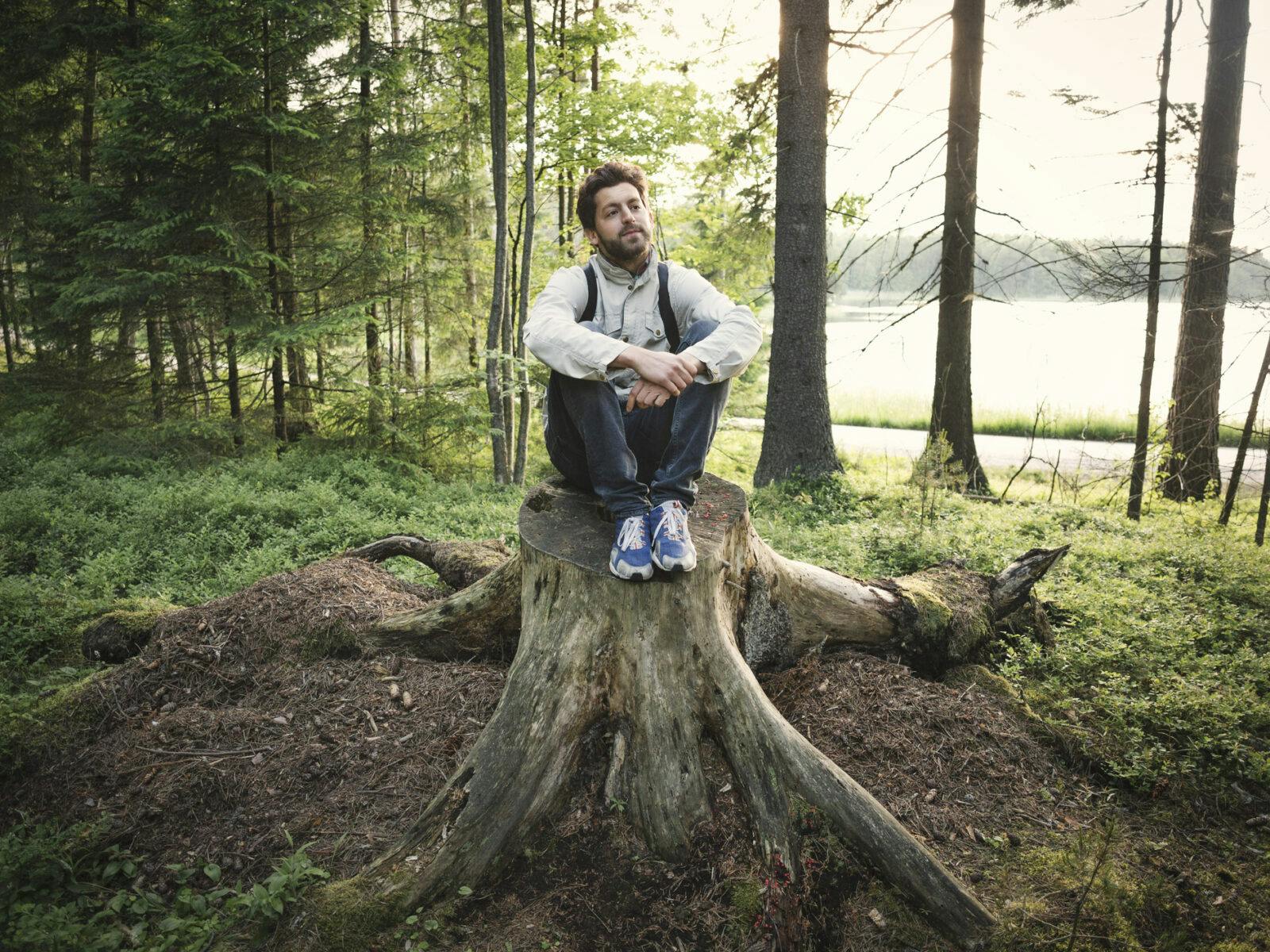 Man som sitter på stubbe i skogen. Bilden har använts till Uppdrag skog.