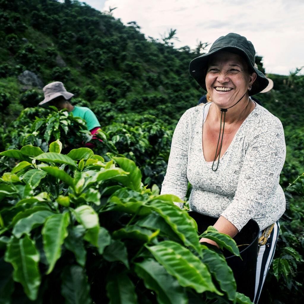 Kvinna som ler på ett kaffeplantage i Colombia.