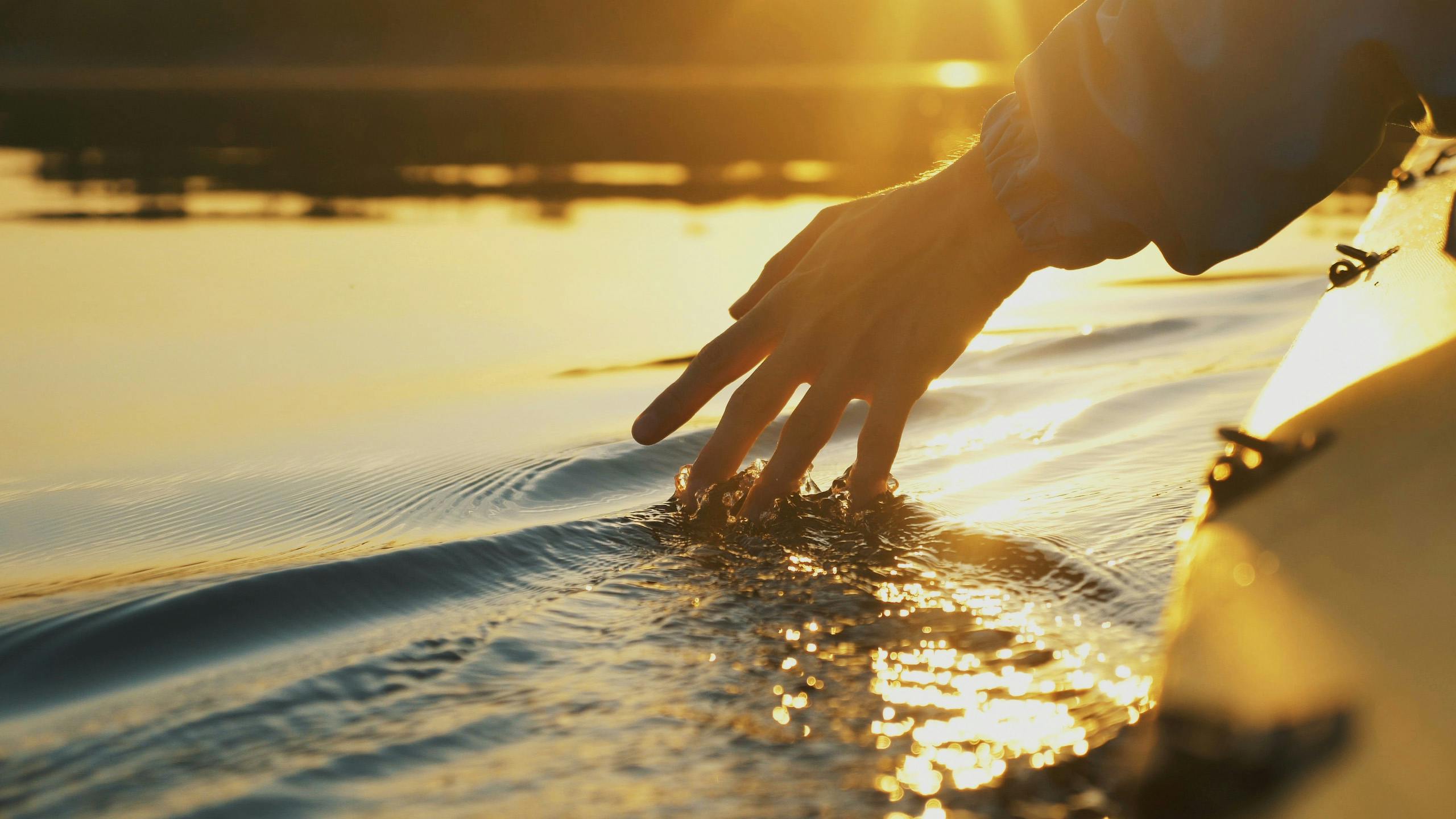Gyllene solnedgång hand i vatten från kanot