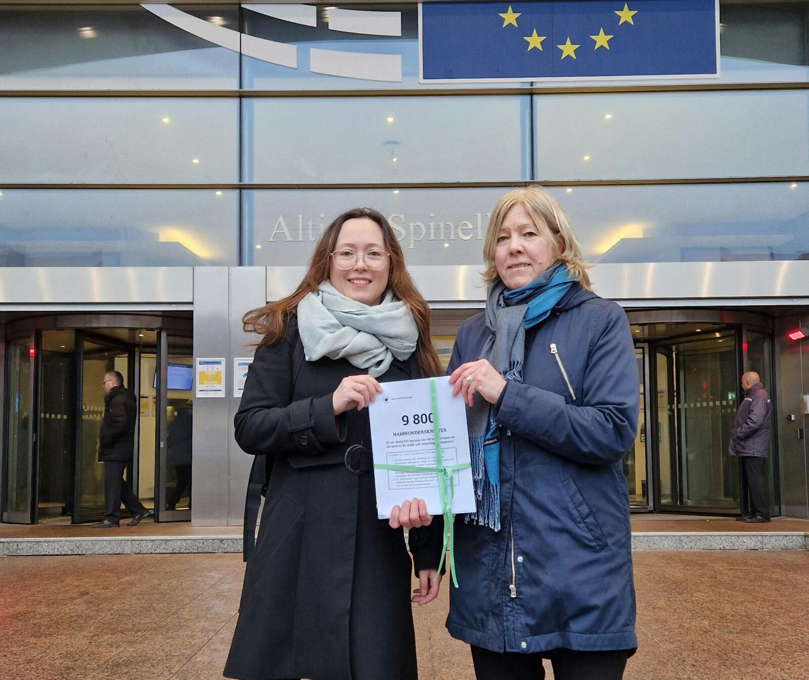 Sofia Tapper och Marja Wolpher framför EU-parlamentet i Bryssel med namninsamlingen för miljöförsvarare.