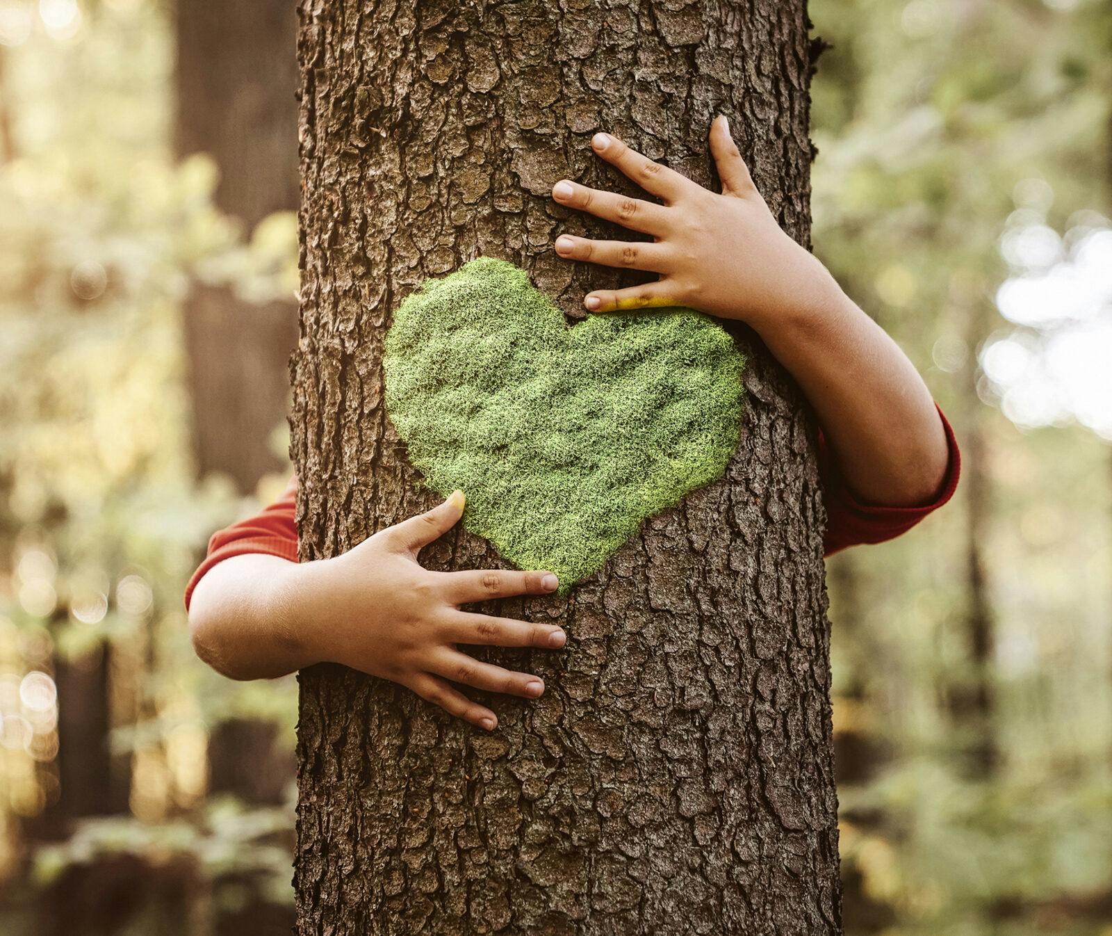 Naturälskande barn kramar om ett träd med ett grönt hjärta på. Jag är Naturskyddare.
