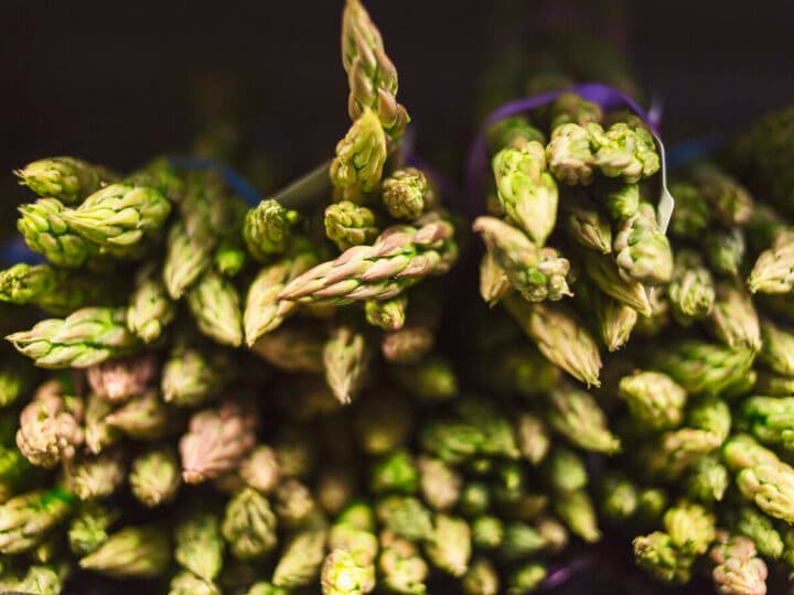 Bilden visar buntar av färsk grön sparris. Sparrisen är tätt packad och har en livlig grön färg.