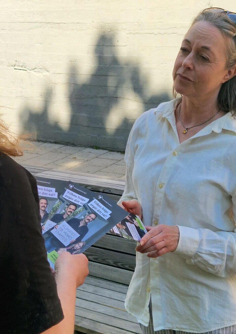 Två personer som prata med varandra och där en person dela ut material till den annan.